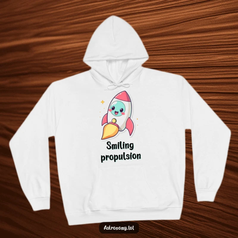 Funny cheerful rocketship character blasting off with a smile, offering cozy comfort and humor on a hoodie.