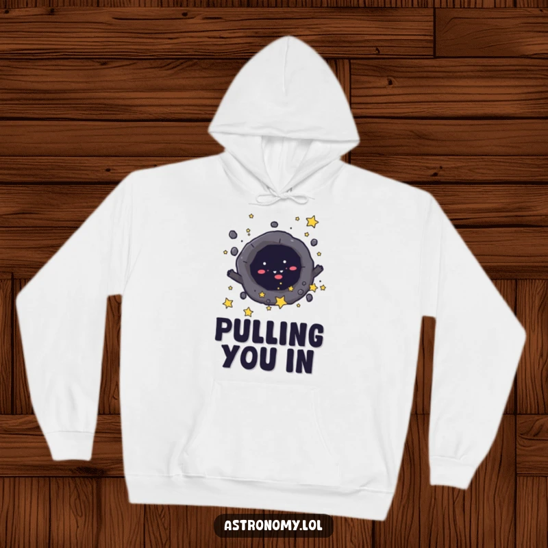 Funny hoodie depicting a mischievous black hole character playfully drawing in tiny stars, offering warmth and dark humor. Great gift.